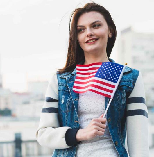 A woman proudly holds an American flag for Immigration Lawyer Naperville