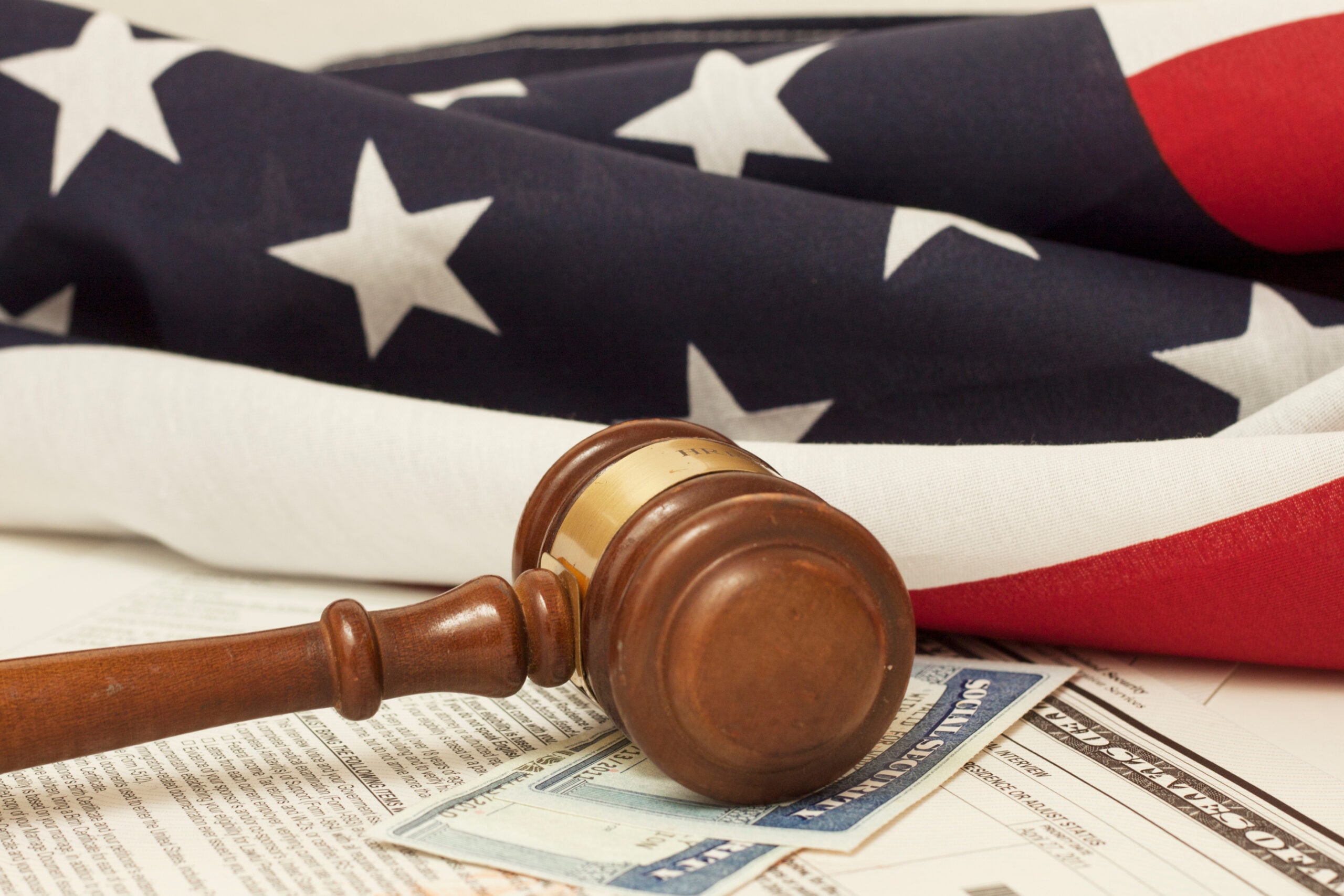 A judge's gavel rests on legal documents and a Social Security card, with a folded American flag in the background—symbolizing the dedication of Chicago immigration attorneys to justice and your path to residency.