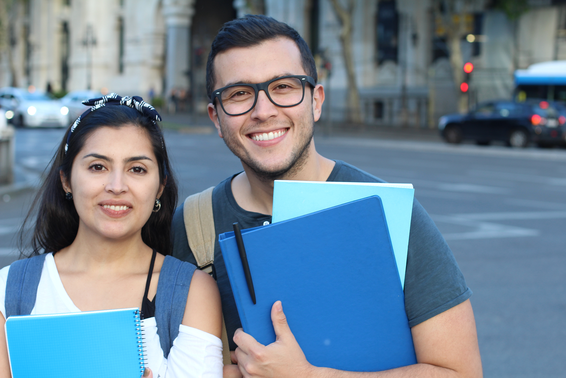 A young man and woman smile while holding books, symbolizing hope and opportunity for those pursuing an EB-3 visa.