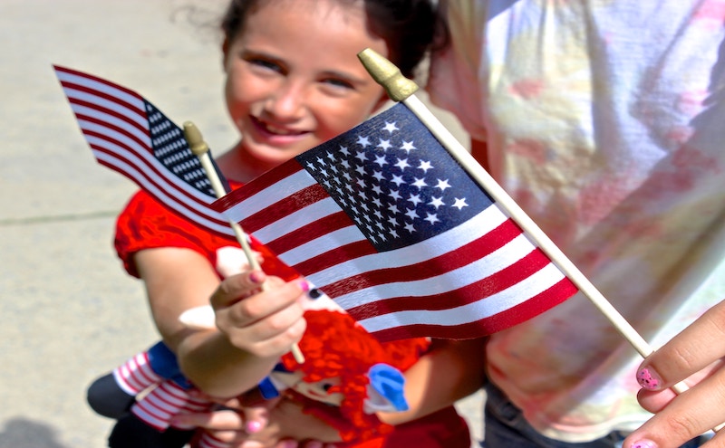 A girl holding small American flags representing birthright citizenship executive order